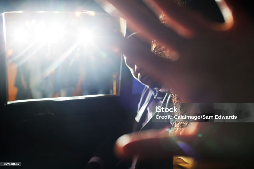 Celebrity couple blocking camera in limousine at event  Covering Stock Photo