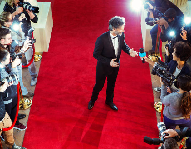 istock Celebrity on red carpet being interviewed and photographed by paparazzi 559538667