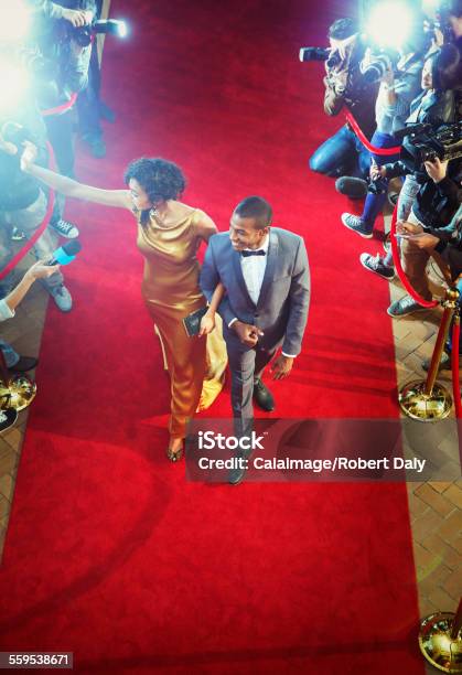 Celebrity Couple Arriving At Event Waving And Walking The Red Carpet Stock Photo - Download Image Now