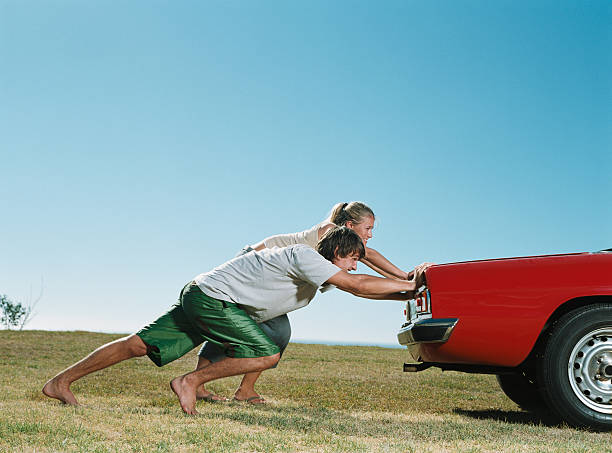 Couple pushing car  Pushing stock pictures, royalty-free photos & images