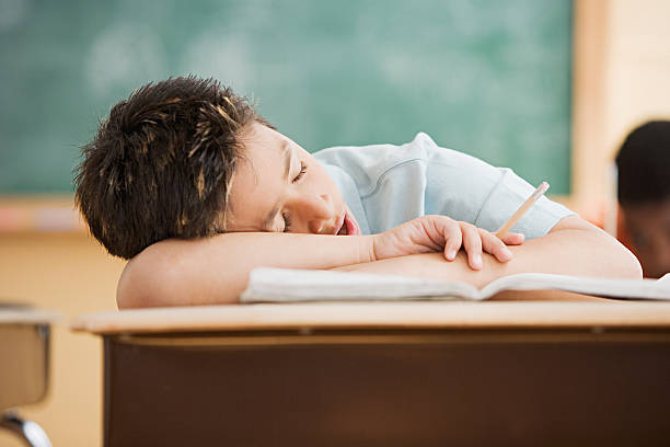 boy sleeping on desk - moe stockfoto's en -beelden