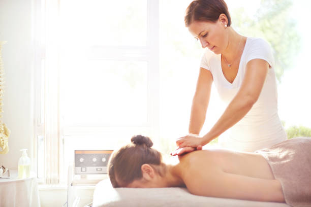 femme recevant un massage par masseuse - spa treatment health spa massage therapist women photos et images de collection