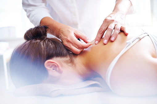 Acupuncturist applying acupuncture needles to womans neck