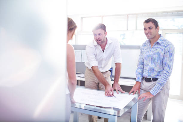 istock Architects reviewing blueprints in meeting in office 562873501