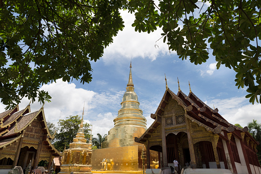 Chiang Mai, Thailand - June 19, 2016: golden stupa pagoda and sanctuary  with leaves frame at Phra Sing Waramahavihan temple. This temple open daily for buddhist and tourist attraction.