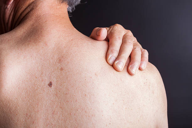 old man holding his shoulder with blackbackground stock photo