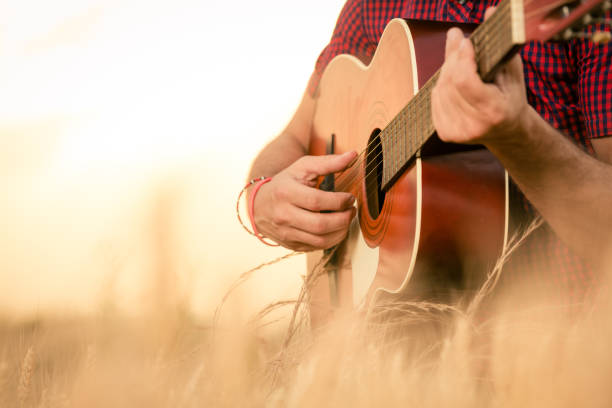 homme jouant de la guitare acoustique sur le terrain - country music photos et images de collection