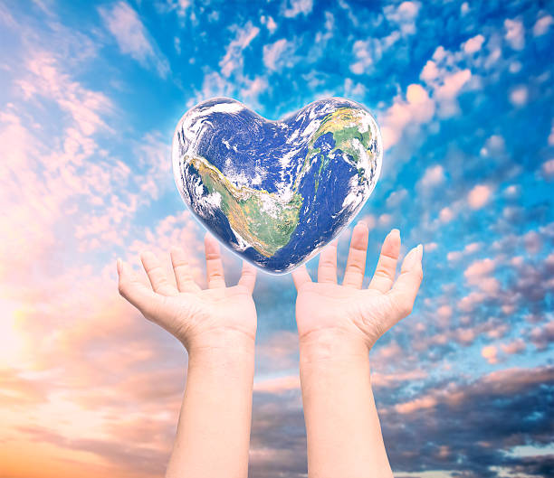 istock World in heart shape with over women human hands 564564616