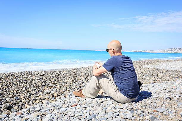 istock Tourist to Nice sitting at beach, texting on his phone 564565504