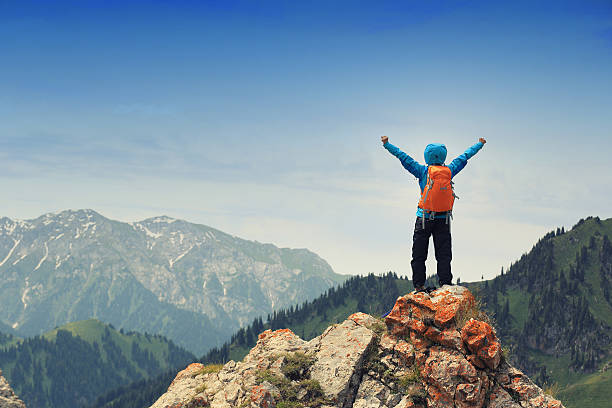 istock cheering successful woman backpacker open arms on mountain peak 564565512
