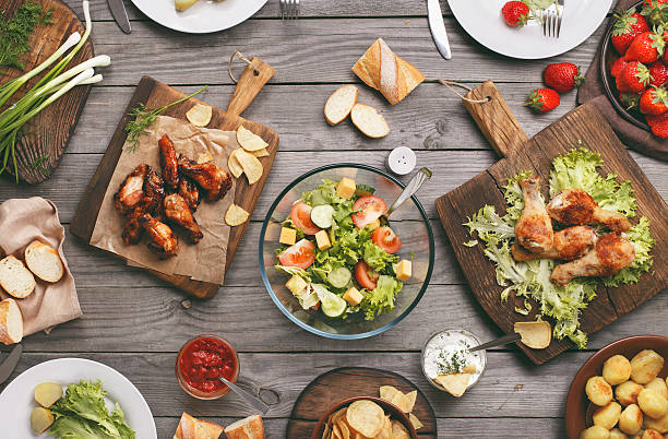 Different food cooked on the grill Different food cooked on the grill on a wooden table, grilled chicken legs, buffalo wings, salad, potatoes and strawberry, top view. Outdoors Food Concept buffalo iowa stock pictures, royalty-free photos & images