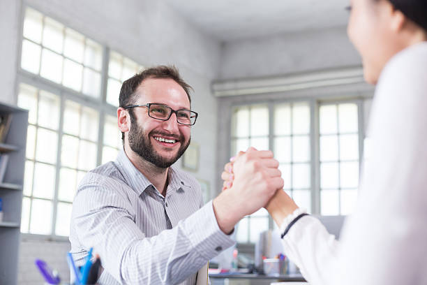 istock Smiling young man in making greeting gesture with female coworker 564566574