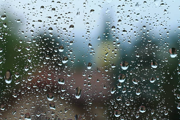 istock Rain drops on window with house and church in background 564567936