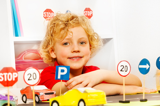 Boy playing driver with toy cars and road signs