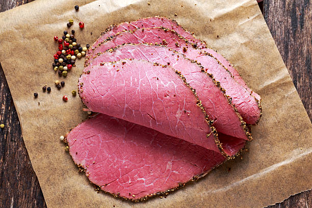 Peppered roast beef pastrami slices on paper with grains of