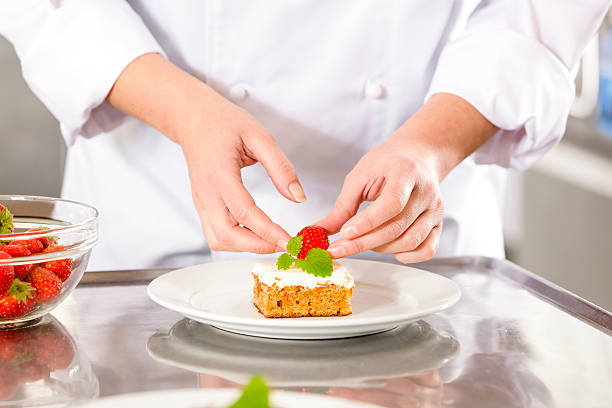 istock Close-up of chef decorating dessert cake with strawberry 564571036