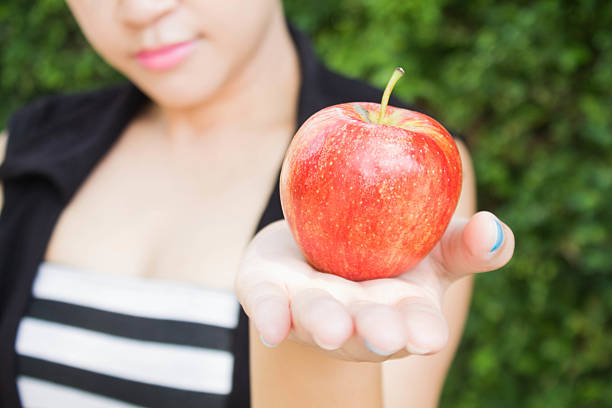 istock Girl's Hand Offering a Red Apple 564572084