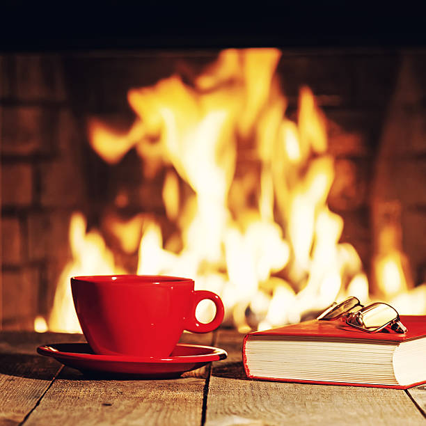 istock Red cup, glasses and old book near fireplace 564573538