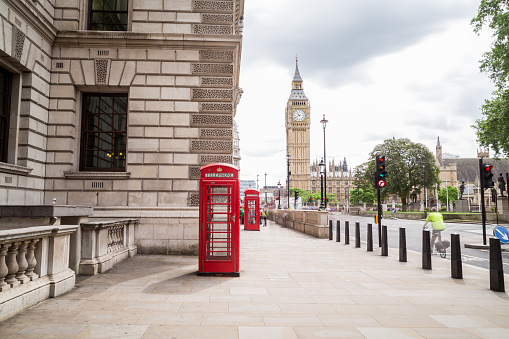 London, UK - June 28, 2016: A view towards Big Ben and Elizabeth Tower during the day. Red Telephone boxes and people can be seen in the foreground.