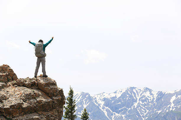 istock cheering successful woman backpacker open arms on mountain peak 564577902