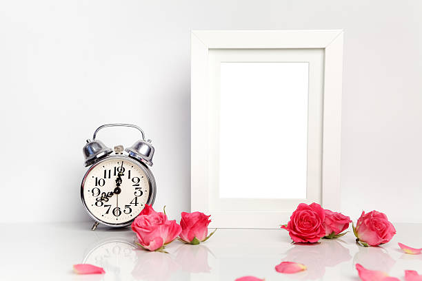 istock Blank white frame, pink roses and alarm clock. Mock up. 564578198