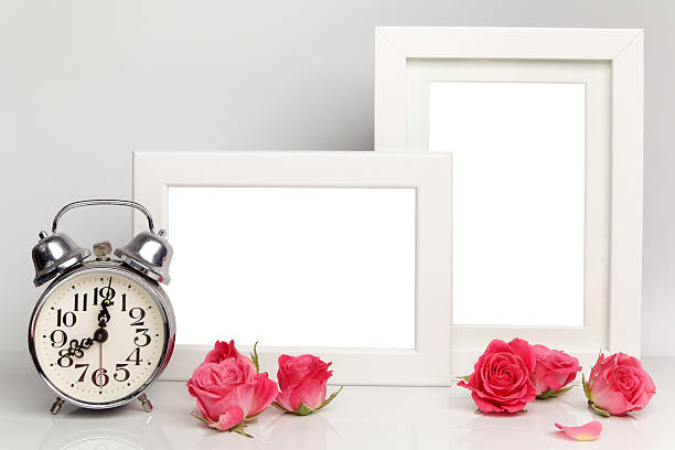 istock Blank white frame, pink roses and alarm clock. Mock up. 564578244