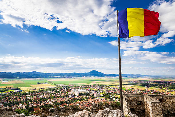 romanian flag flying above the town of rasnov, transylvania, romania - romania flag romanian flag colors imagens e fotografias de stock