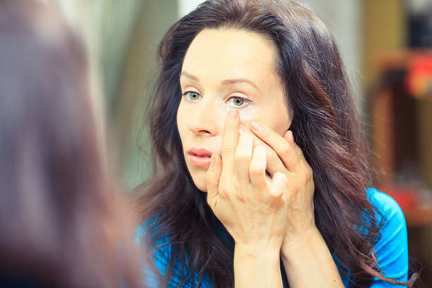 Close up of a woman putting contact lens in eye. Young brunette woman holding contact lens on finger in front of her eye river wear stock pictures, royalty-free photos & images