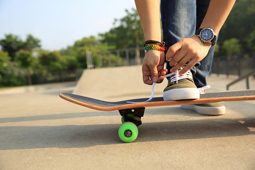 skateboarder tying shoelace at skatepark ramp