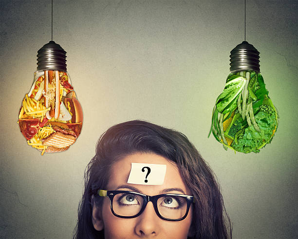 istock Woman thinking looking at junk food and vegetables light bulb 564594624