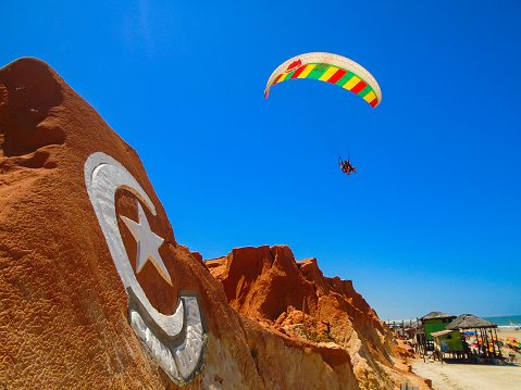 Fortaleza, Brazil - October 12, 2015: Unidentified people and paragliders at the Canoa Quebrada Beach. It was a Swiss pilot who introduced this new practice: Gerome Bertand Saunier, best known as Jeronimo