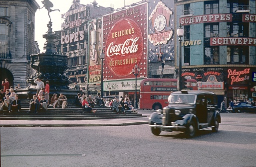 London,England,UK, Mai 22, 1968. The famous Piccadilly Circus to the Regant Street. Left the Shaftesbury Memorial Fountain. On the Steps at the Base sitting young People, Londoners and Tourists. They see the world go by on the busy square.
