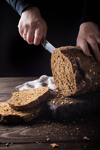 istock Female hands slicing homemade multigrain bread 564601834