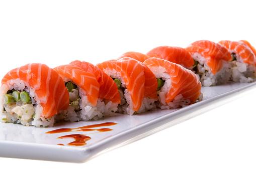 Sliced salmon sushi roll displayed on a white tray.