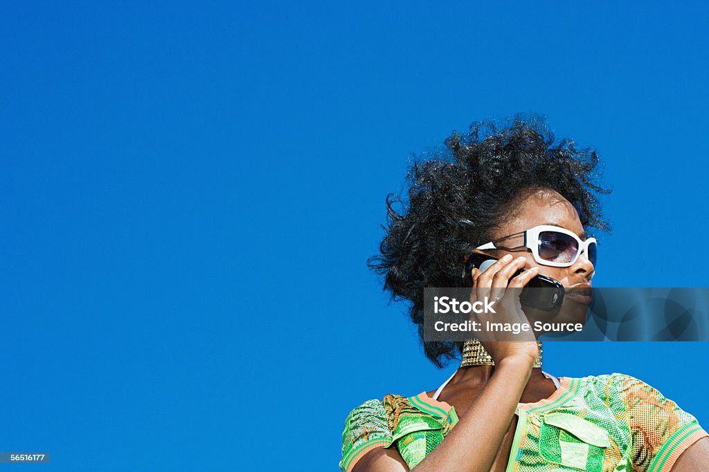 Giovane donna utilizzando un telefono cellulare - Foto stock royalty-free di Abbigliamento