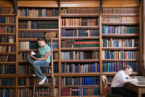 A student stuying and reading books in a public library of university.