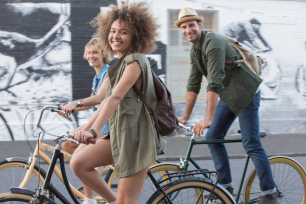 portrait smiling friends riding bicycles on urban street - cycling bicycle women city life imagens e fotografias de stock