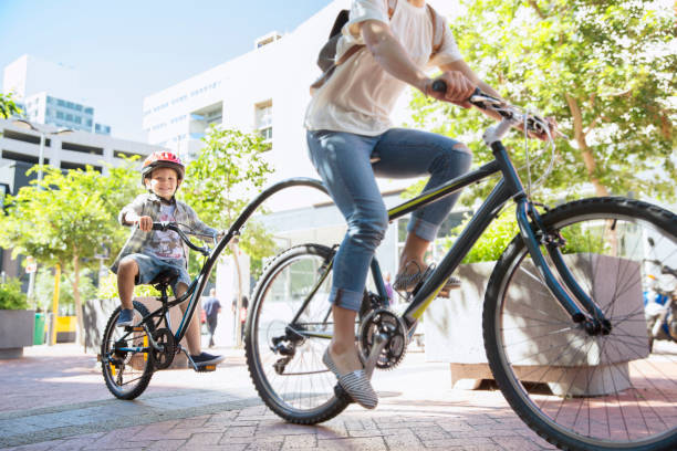 son in helmet riding tandem bicycle with mother in urban park - cycling bicycle women city life imagens e fotografias de stock