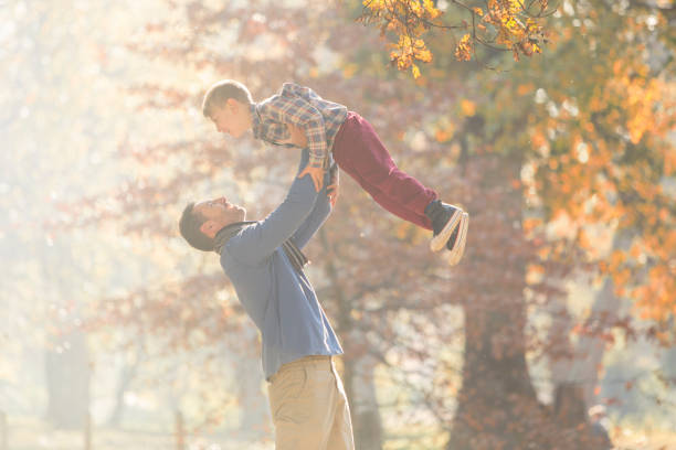 istock Father lifting son overhead in woods with autumn leaves 568517995