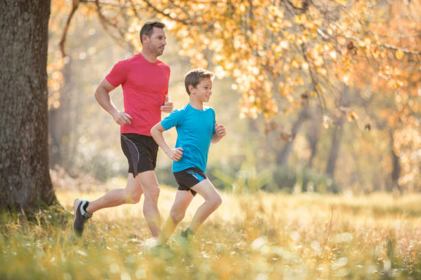 Father and son jogging, woman cycling and people walking in background.