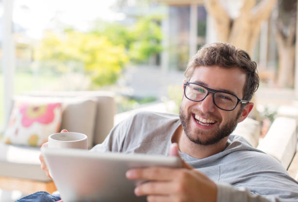 retrato hombre sonriente bebiendo café y usando tableta digital - sólo hombres jóvenes fotografías e imágenes de stock