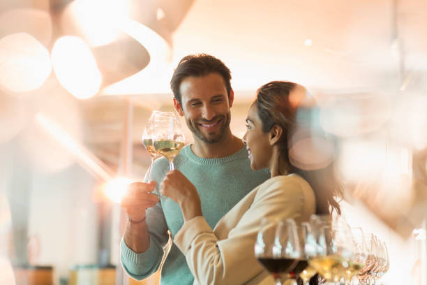 дегустация парных вин в солнечном дегустационном зале винодельни - standing smiling two people 30s стоковые фото и изображения