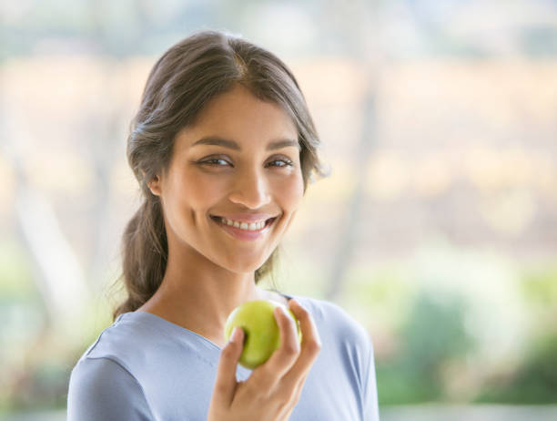 primo piano ritratto sorridente donna che mangia mela verde - apple women green eating foto e immagini stock