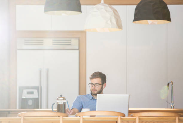 homem escrevendo no laptop na cozinha com café francês imprensa - coffee pot audio - fotografias e filmes do acervo