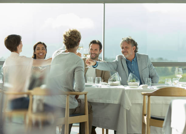 istock Friends toasting wine glasses at sunny restaurant table 568519175
