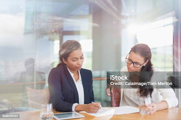Businesswomen Reviewing Paperwork In Conference Room Stock Photo - Download Image Now