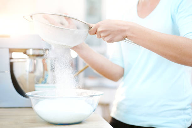 istock Woman sifting flour and baking in kitchen 568519587