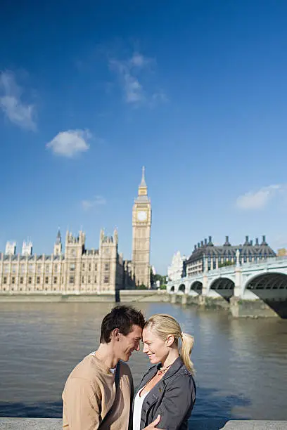 Photo of Couple by river near Houses of Parliament