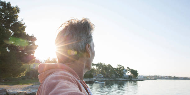 istock Man looks across tranquil sea at sunrise 570263041