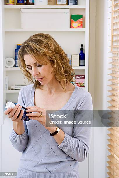 Woman Looking At Medicine Bottle 메디컬 캐비닛에 대한 스톡 사진 및 기타 이미지 - 메디컬 캐비닛, 가정 생활, 기침 치료제